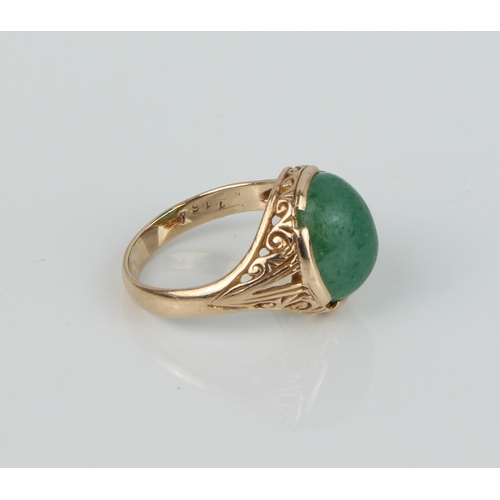 184 - A 9ct yellow gold and jade-style ring - with a scroll carved setting, size Q.