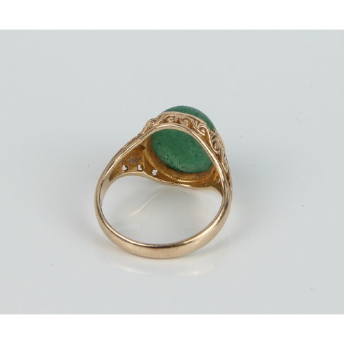 184 - A 9ct yellow gold and jade-style ring - with a scroll carved setting, size Q.