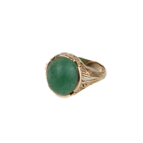 184 - A 9ct yellow gold and jade-style ring - with a scroll carved setting, size Q.