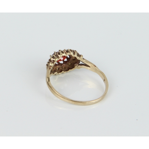 212 - A 9ct yellow gold, garnet and seed pearl cluster ring - hallmarked Birmingham 1989, the oval cut gar... 