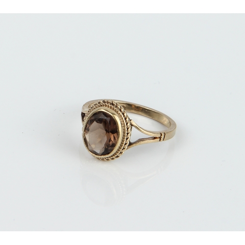 243 - A 9ct yellow gold and smoky quartz ring - the oval cut smoky quartz, approx. 9 x 7mm, in a rope twis... 