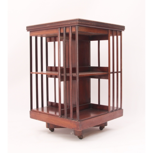 428 - An early 20th century mahogany revolving bookcase - two-tier, on an X-frame base with pottery castor... 