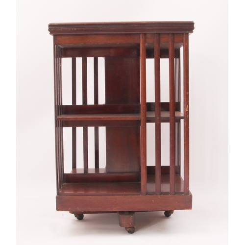 428 - An early 20th century mahogany revolving bookcase - two-tier, on an X-frame base with pottery castor... 