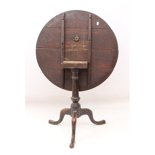 483 - A George III oak tilt-top tripod table - the circular top on a turned gun-barrel column to three swe... 