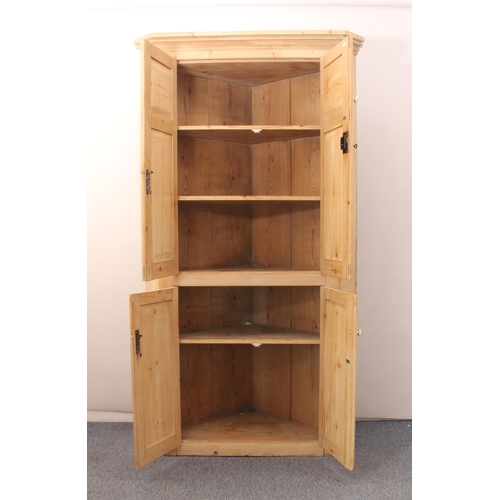 505 - A stripped pine floorstanding corner cupboard in the early 19th century style - the moulded cornice ... 