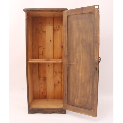 514 - A narrow stained pine cupboard - early 20th century, the panelled door enclosing a two-shelf interio... 