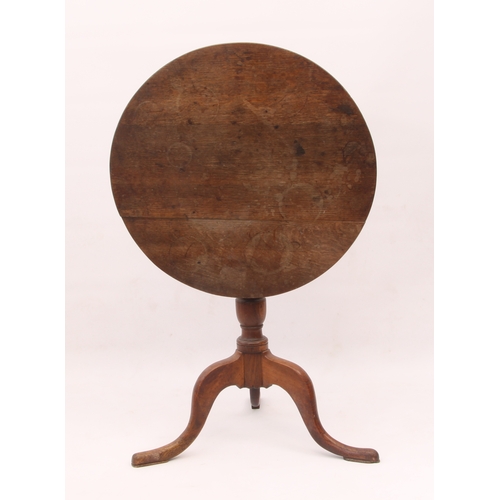 518 - A George III oak tilt-top tripod table - the circular top on a turned gun-barrel column to three swe... 