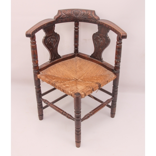 525 - A Victorian carved oak corner chair - carved with flowers and stylised foliage, over a rush seat (a/... 