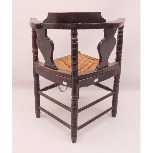 525 - A Victorian carved oak corner chair - carved with flowers and stylised foliage, over a rush seat (a/... 