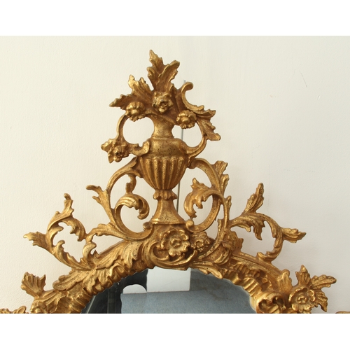 573 - A George II style carved gilt wood mirror - late 20th century, the oval plate within a floral and fo... 