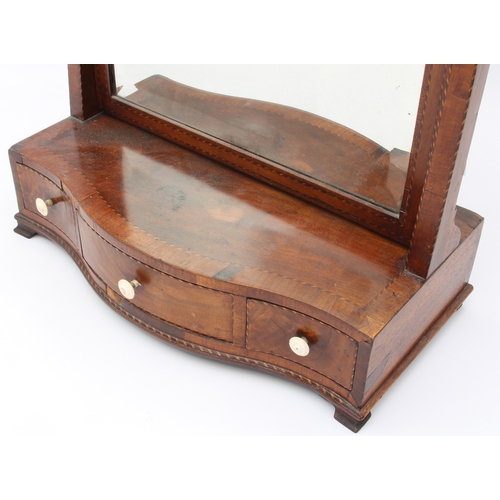 576 - A George III crossbanded mahogany serpentine box-base toilet mirror - the arched, bevelled plate on ... 