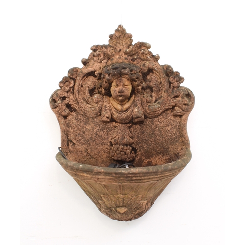 600 - A terracotta coloured composite stone garden wall-mounted water fountain - with mask, foliate scroll... 