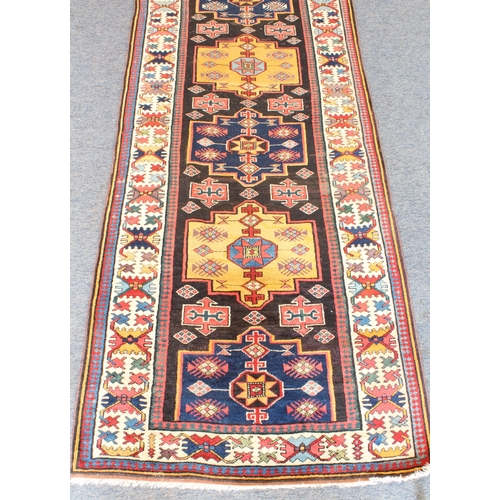 622 - A good Kazak runner - c.1900, with nine central lozenge medallions in blue and deep yellow on a dark... 