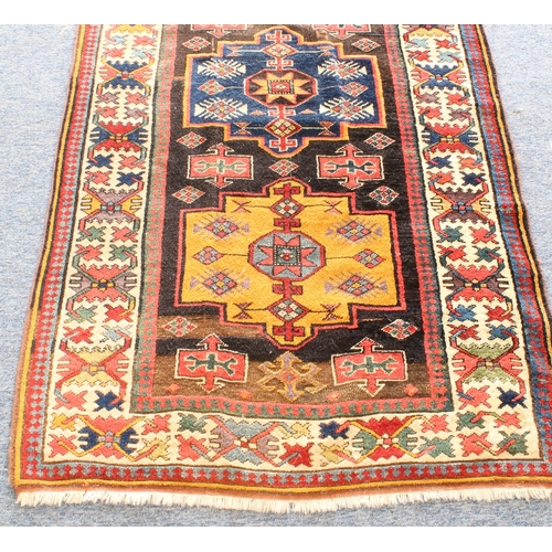 622 - A good Kazak runner - c.1900, with nine central lozenge medallions in blue and deep yellow on a dark... 