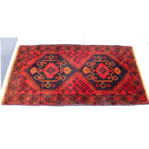 645 - A Turkish rug - late 20th century, the red ground with two joined very deep blue lozenge medallions ... 