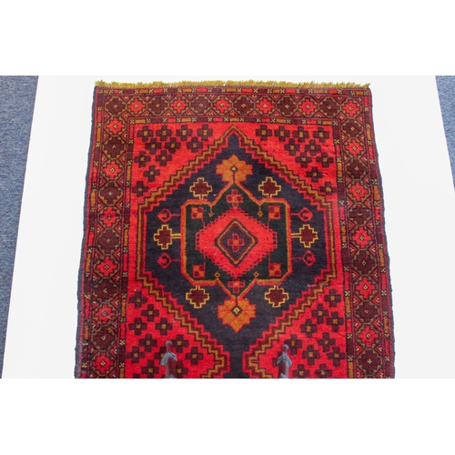 645 - A Turkish rug - late 20th century, the red ground with two joined very deep blue lozenge medallions ... 