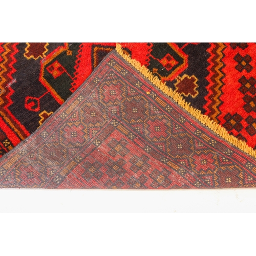 645 - A Turkish rug - late 20th century, the red ground with two joined very deep blue lozenge medallions ... 