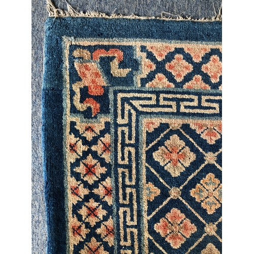 605 - A small Chinese wool rug - mid-20th century, with all over floral decoration on a blue ground, withi... 