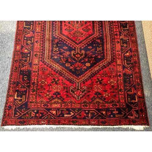 609 - A Hamadan hand-knotted wool rug - late 20th century, the dark-blue and red lozenge hooked pendant me... 