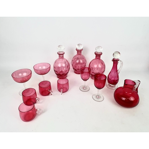 100 - A collection of antique and later cranberry glass - including a pair of claret jugs with moulded qui... 