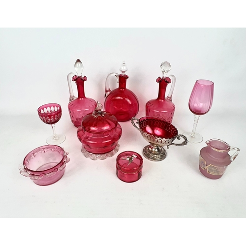 100 - A collection of antique and later cranberry glass - including a pair of claret jugs with moulded qui... 