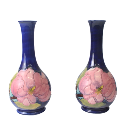 9 - A pair of Moorcroft 'Magnolia' pattern bottle vases - the pink flowers on a dark blue ground, one wi... 