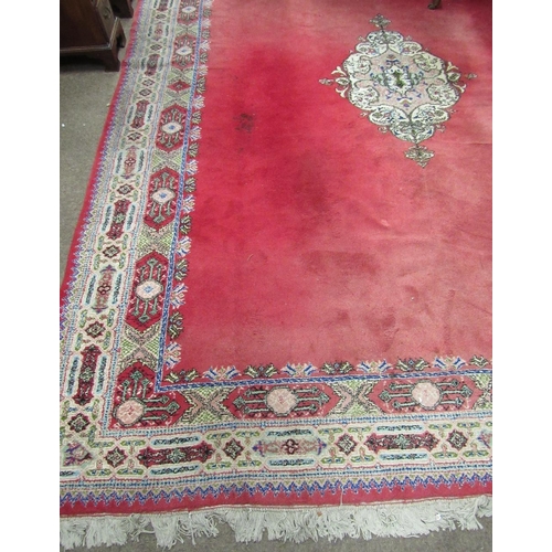 705 - A large burgundy ground Oriental Carpet, with plain centre and decorative floral pattern border, 13'... 