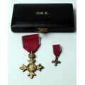 A cased silver gilt OBE Medal, with matching miniature by the Royal Mint, both with red ribbons and ... 