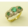 An attractive three stone emerald Ring, with a halo of 24 diamonds set in white gold with yellow sha... 