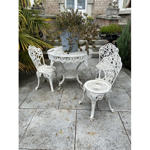 130 - A four piece cast metal Patio Set, comprising a heavy circular table with open work top on four shap... 