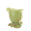 A fine carved Chinese jade Libation Cup, carved in relief with scrolls under a double spout and two ... 