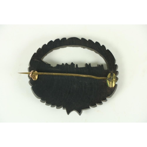 867 - A rare 19th Century Irish carved bog oak Brooch, with view of Howth Castle, in a carved oval wreath,... 