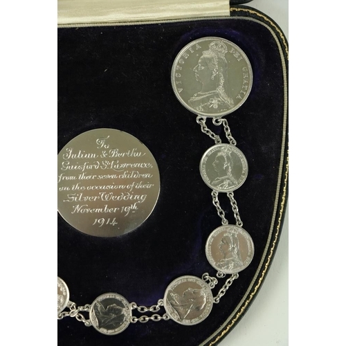 878 - A cased set of Victorian and George V silver Coins, with chain link, with inscribed central coin 