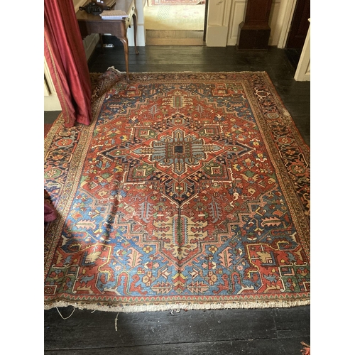 343 - A large Persian Carpet, with diamond medallion and all-over geometric designs, on iron red ground wi... 