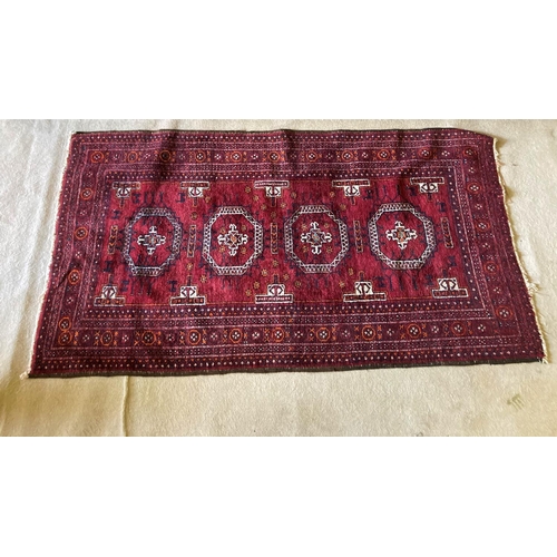 381 - A red ground Bokhara Rug, with four octagons inside a multi band border, 76