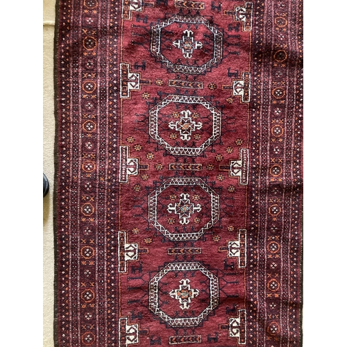 381 - A red ground Bokhara Rug, with four octagons inside a multi band border, 76