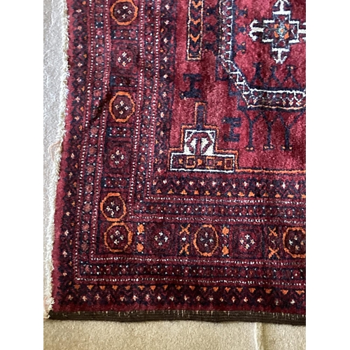 381 - A red ground Bokhara Rug, with four octagons inside a multi band border, 76