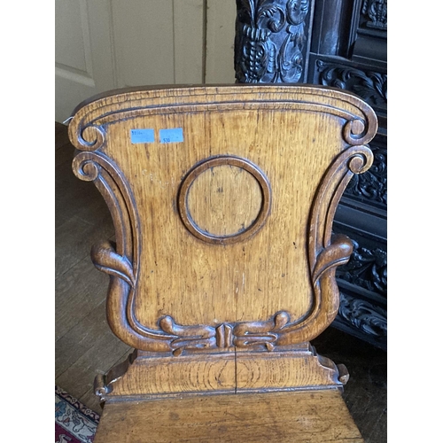 530 - A set of three Victorian heavy oak shield back Hall Chairs, the shaped and carved backs over plain s... 