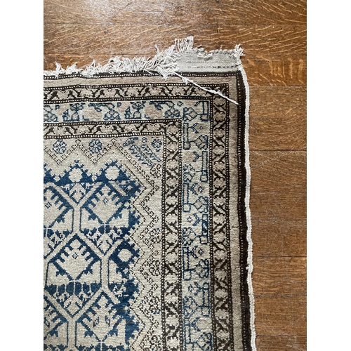 578 - An Afghan Rug, with rows of octagons on a faded ivory field with a multi banded border,approx. 10'7