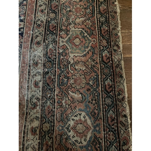 580 - An antique Persian Carpet, with all over stylized pattern on a dark blue and red ground inside an ir... 