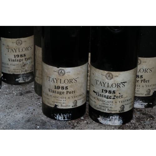 584 - Twelve Bottles of Taylors 1985 Vintage Port, (imported by Woodforde Bourne), labels worn and damp da... 