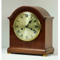 An Edwardian stained oak cased Mantle Clock, the arched top over silvered dial with Roman numerals o... 