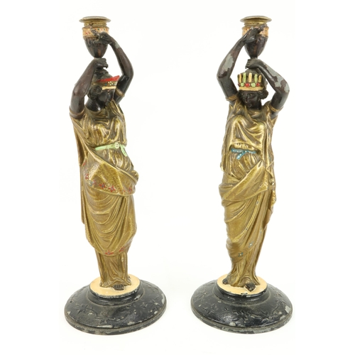 66 - An attractive pair of hand painted spelter Candlesticks, modelled as female Egyptian servants, appro... 