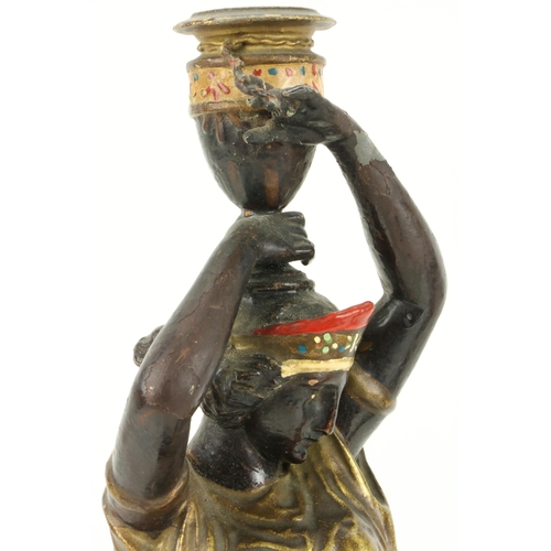 66 - An attractive pair of hand painted spelter Candlesticks, modelled as female Egyptian servants, appro... 