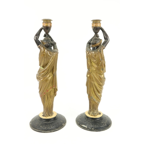 66 - An attractive pair of hand painted spelter Candlesticks, modelled as female Egyptian servants, appro... 