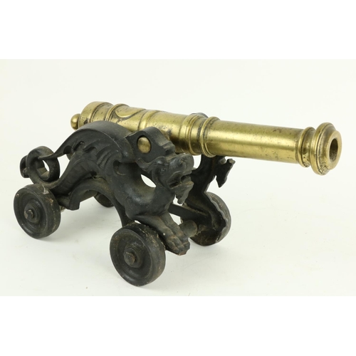 222 - A heavy brass Floor Cannon, on cast iron dragon form carriage and four cast iron wheels, 18