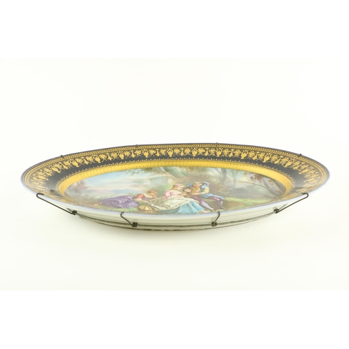 259 - A large oval Serves style porcelain Platter, depicting three figures in a garden landscape, inside a... 