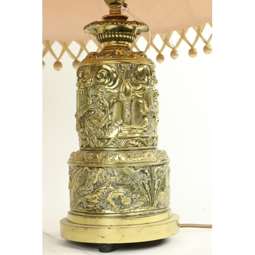 273 - An embossed brass Table Lamp, the two stage body with classical figures in relief supporting an ivor... 