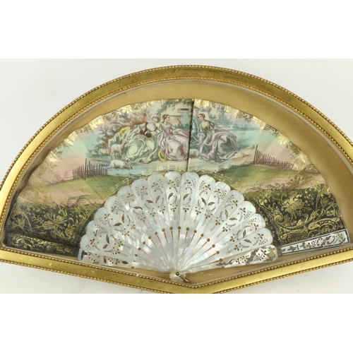 354 - An attractive framed Ladies hand painted silk and mother-o-pearl Fan, depicting Ladies resting by a ... 