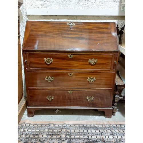 1084 - A George III period mahogany slope front Bureau, with fitted interior above three long drawers on br... 